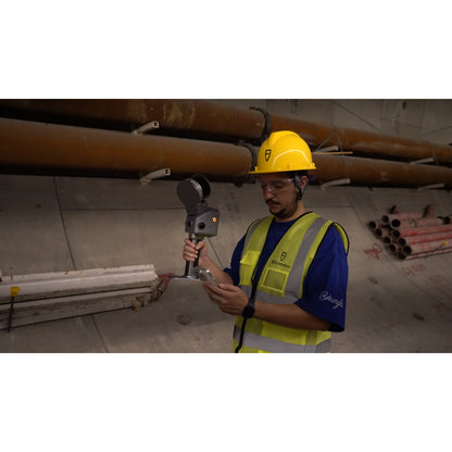 A construction worker stands on a job site, holding a handheld FJD Trion T1 for surveying and measurement.