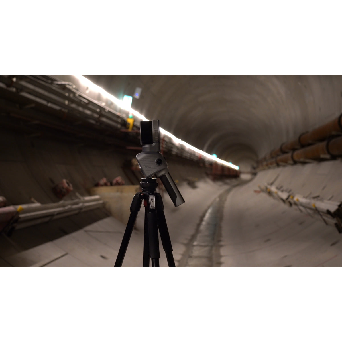 FJD Trion T1 mounted on a tripod for terrestrial laser scanning inside a concrete tunnel with overhead lighting.