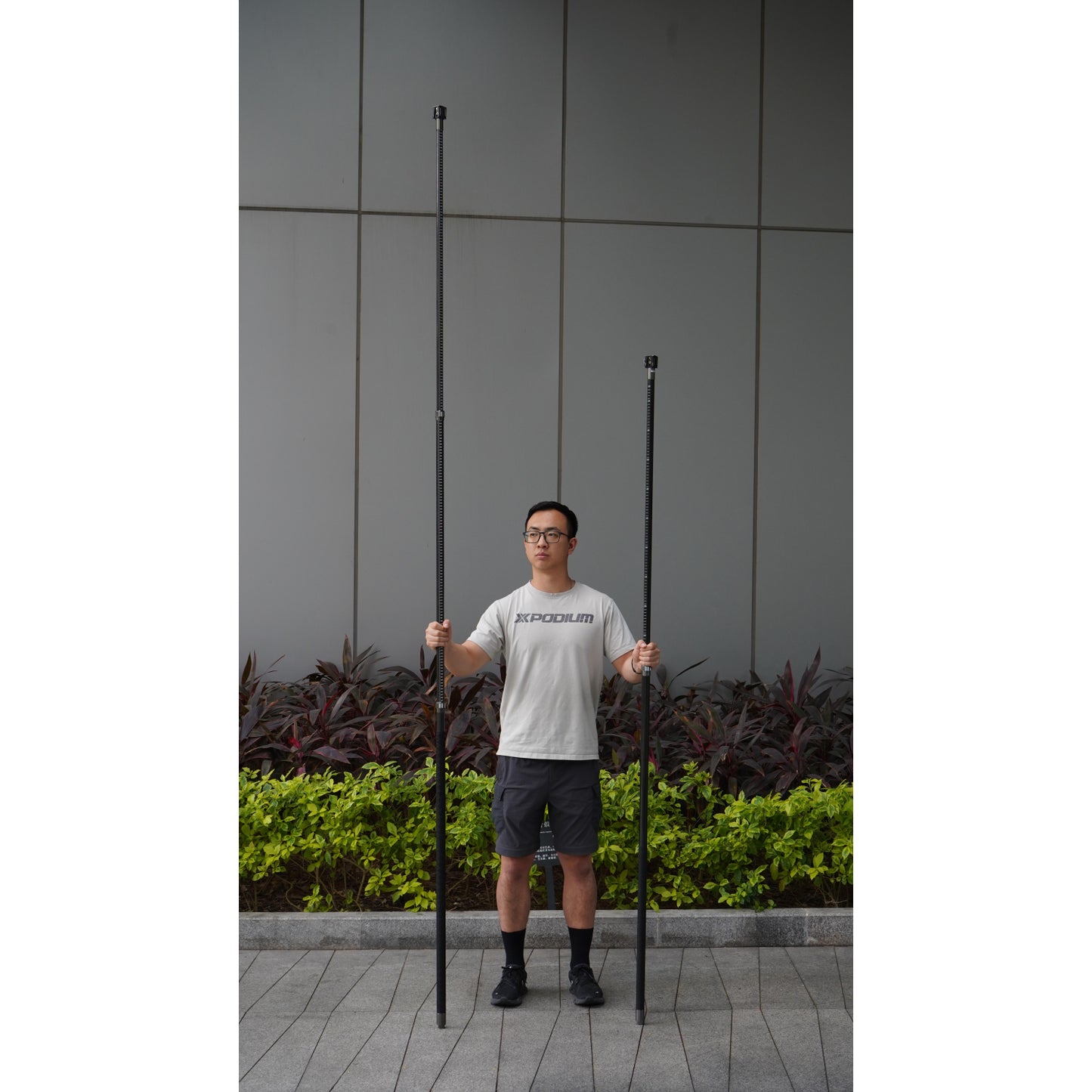 a surveyor comparing the lengths between XGRIDS K1 extension pole kit 2m and 3m modular system for elevated mobile LiDAR mapping and survey-grade stability