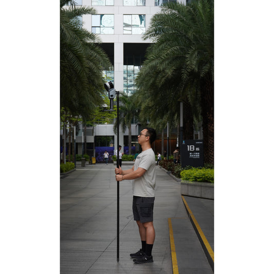 a surveyor using the XGRIDS K1 extension pole kit modular system for elevated mobile LiDAR mapping and survey-grade stability in a business park with XGRIDS Lixel L2 attached 