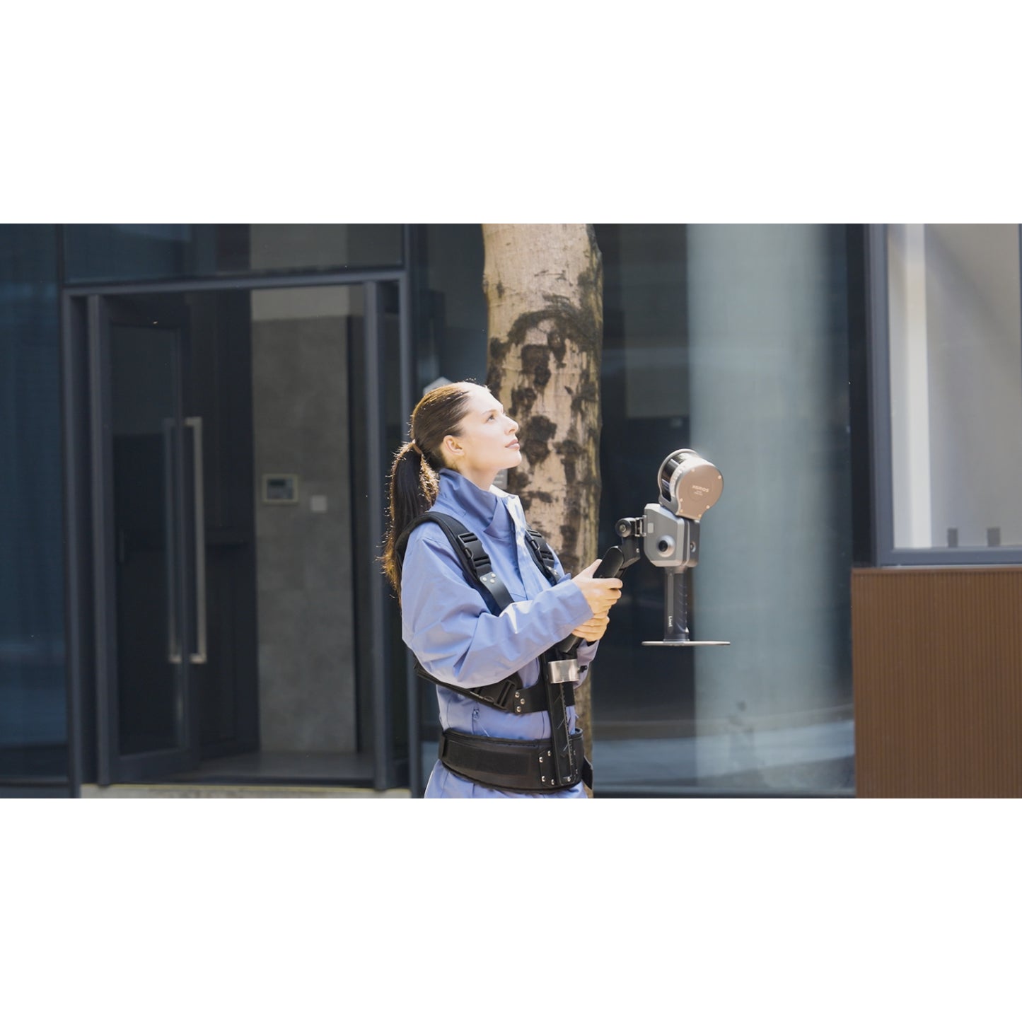 surveyor using XGRIDS Lixel L2 Pro real-time RTK SLAM LiDAR scanner for scanning the outdoor areas of a business complex in sunlight